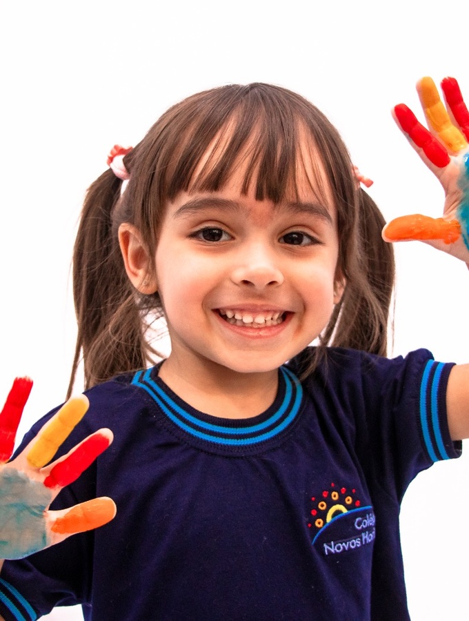 Criança com as mãos pintadas em atividade de Educação Infantil